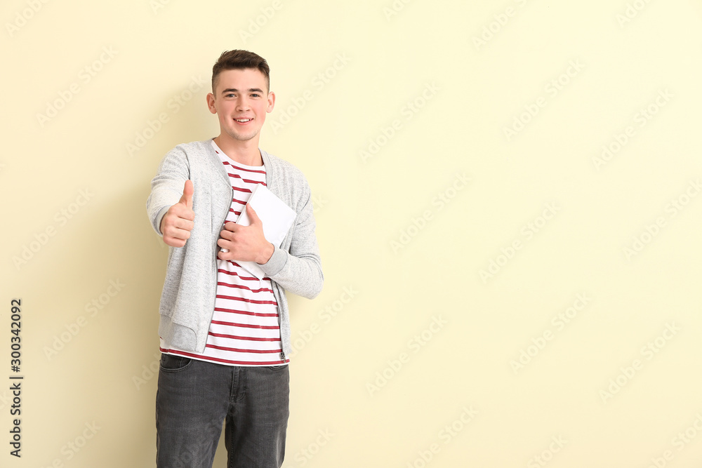 Portrait of teenage schoolboy showing thumb-up on color background Portrait of teenage schoolboy showing thumb-up on color background