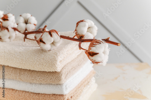 Soft clean towels with cotton flowers on table photo