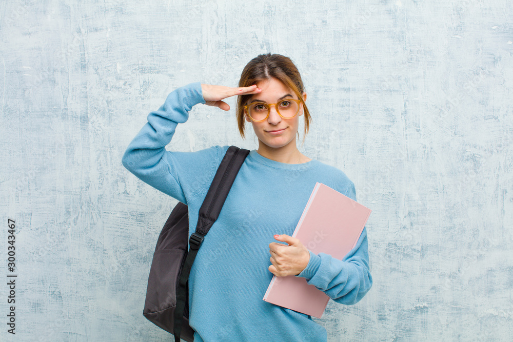 Φωτογραφία young student woman greeting the camera with a military salute in an act of hono