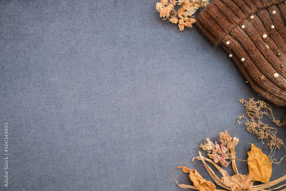 Autumn winter flat lay. Brown knitted beanie and dry leaves on blue blank background. Autumn winter flat lay. Brown knitted beanie and dry leaves on blue blank background.
