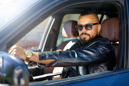 Confident stylish bearded man in sunglasses driving a car © paultarasenko