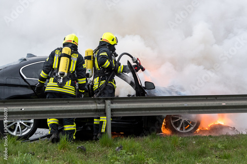 Feuerwehrmänner löschen ein brennendes Auto photo