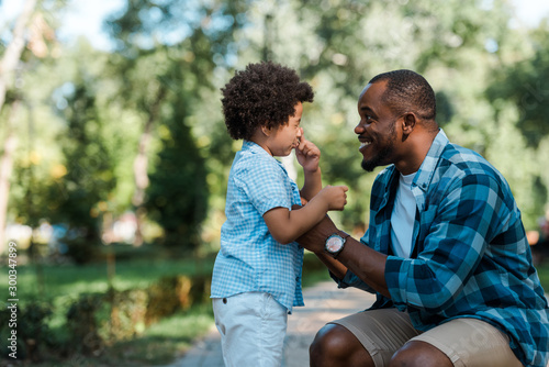 happy african american man looking at frustrated curly son