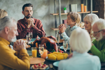 Big family celebrate thanksgiving day sit table have large feast meal food roasted meat corns alcohol pray in house indoors