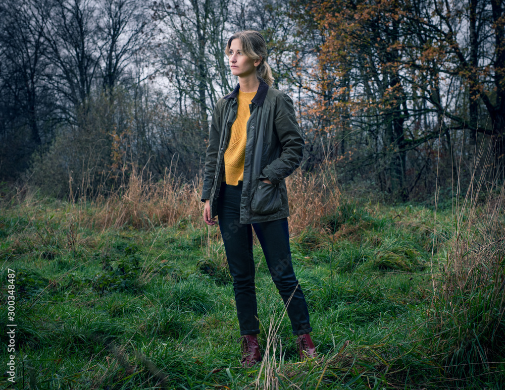 Portrait of a blonde woman standing in a forest with hand in her pocket Portrait of a blonde woman standing in a forest with hand in her pocket