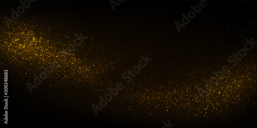 Golden particles, sparkling glitter dust on dark background.
