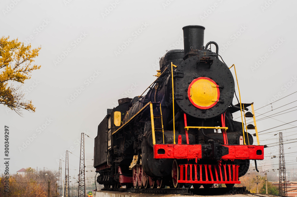 Fototapeta premium Old steam train on rails near the railway station in the fall.