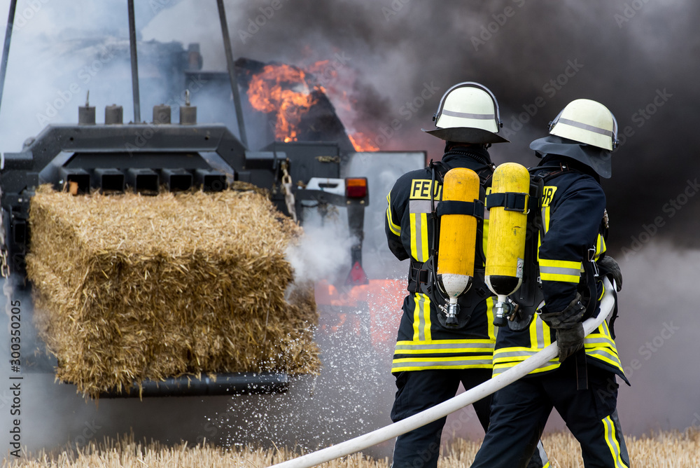 Obraz premium Die Feuerwehr löscht einen brennenden Traktor