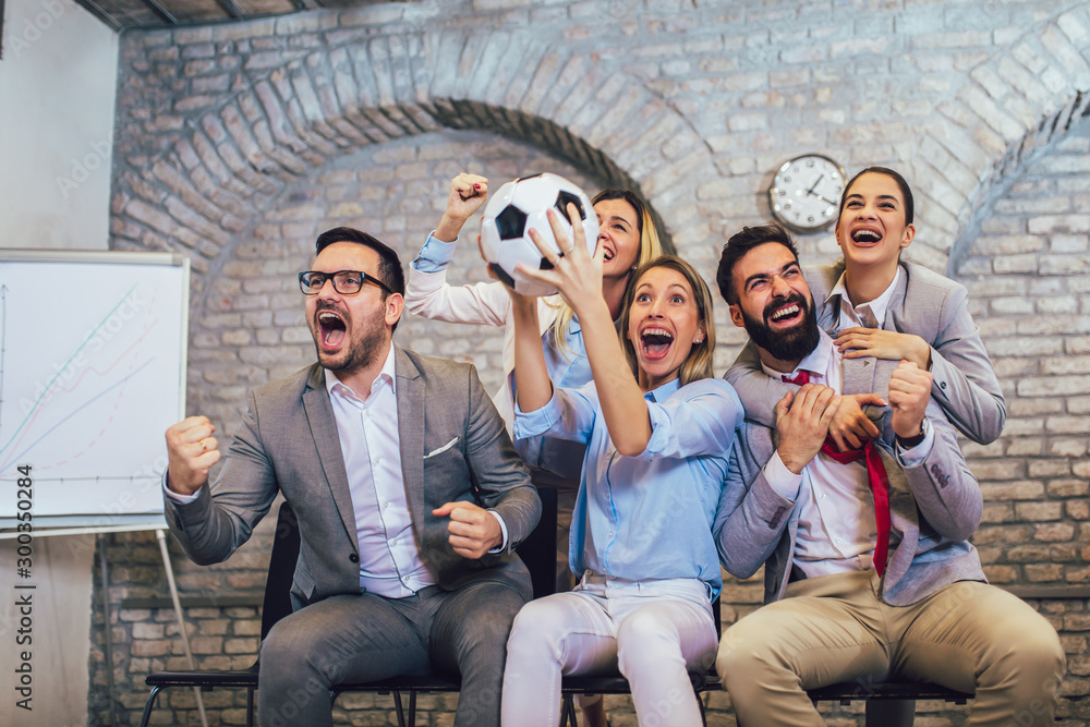 Naklejka premium Happy business people or football fans watching soccer on tv and celebrating victory. Friendship, sports and entertainment concept.