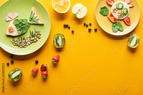 top view of plates with fancy fish and cow made of food on colorful orange background