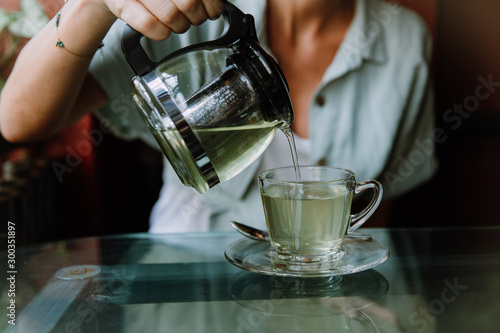 Woman pouring herbal tea into a glass cup