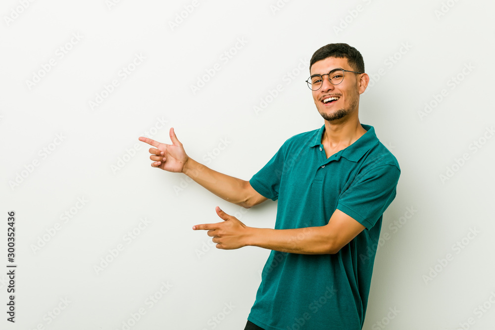 Young hispanic man excited pointing with forefingers away. Young hispanic man excited pointing with forefingers away.