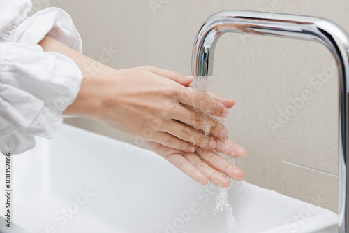 Women open faucets in the bathroom to wash hands, remove dirt and bacteria.