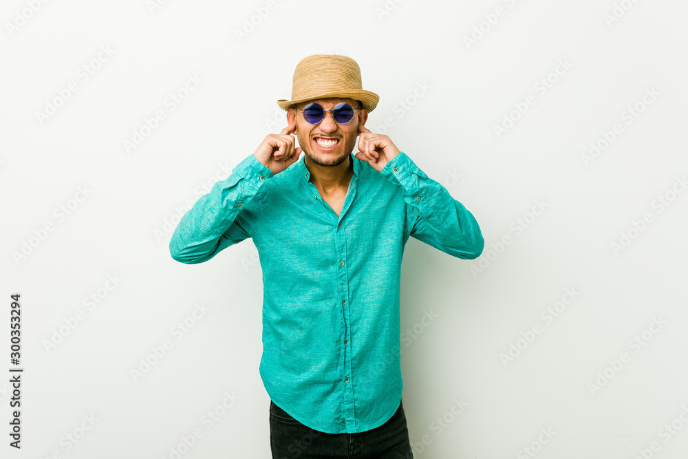 Young hispanic man wearing a summer clothes covering ears with hands. Young hispanic man wearing a summer clothes covering ears with hands.
