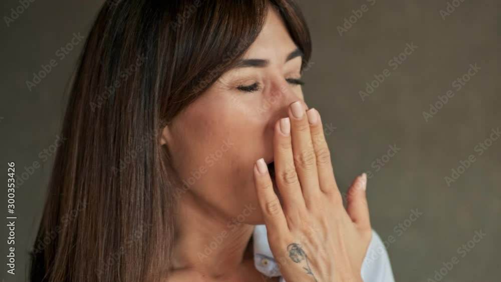 Close up view of pretty calm young business woman yawning and taking her eyeglasses on while working at home Close up view of pretty calm young business woman yawning and taking her eyeglasses on while working at home