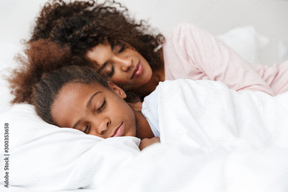 Image of african american woman and her little daughter sleeping together