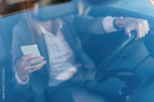Close-up of woman using smart phone while driving a car.