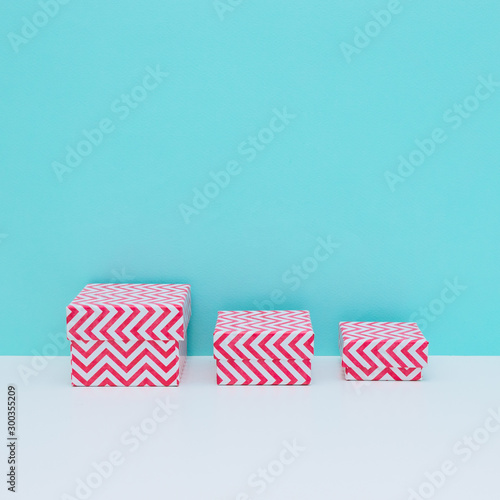 Three sized gift boxes for winter holiday, Christmas or New Year on white and  light blue background. Minimalism, copy space
