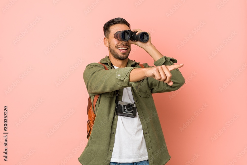 Young south-asian man looking through a binoculars. Young south-asian man looking through a binoculars.