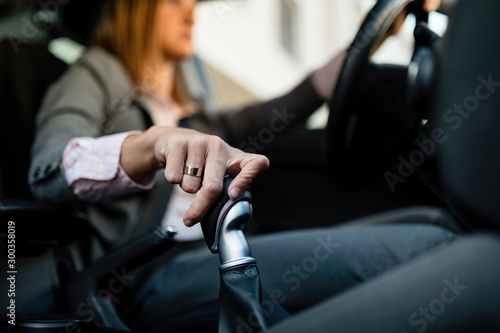 Close-up of businesswoman shifting gear while driving a car.