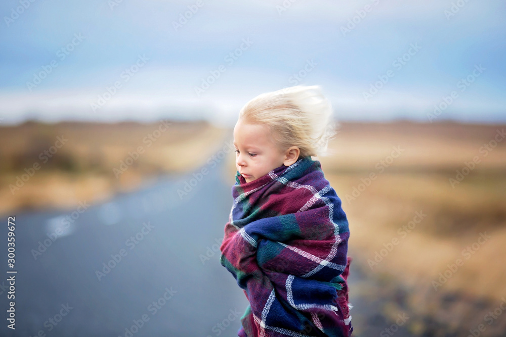 Beautiful child, standing on a road on a very windy day, wrapped in scarf, watching the sunrise in Iceland Beautiful child, standing on a road on a very windy day, wrapped in scarf, watching the sunrise in Iceland
