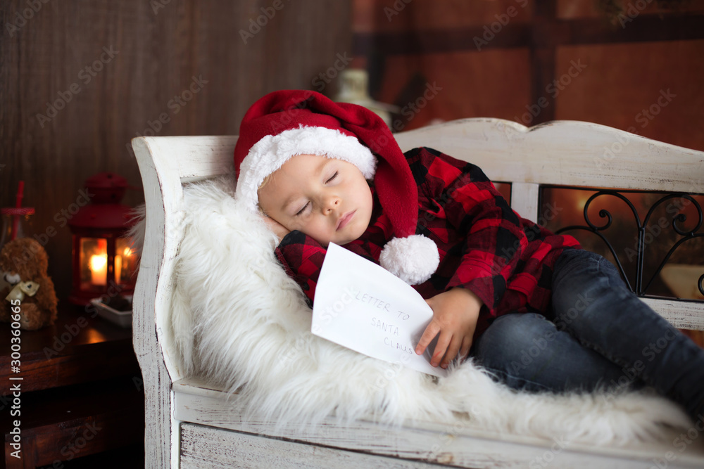 Obraz premium Sweet blonde toddler boy, sleeping with letter to Santa in hand, wishing present for the holidays