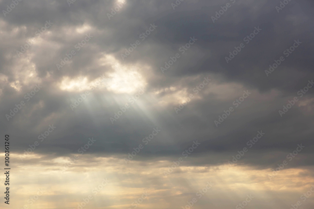 Background image of a dramatic overcast sky with rain clouds through which the sun looks out.