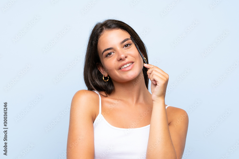 Young girl holding makeup brush over isolated background Young girl holding makeup brush over isolated background