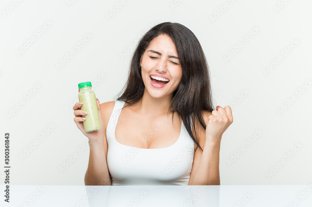 Young hispanic woman holding a vegetable drink cheering carefree and excited. Victory concept. Young hispanic woman holding a vegetable drink cheering carefree and excited. Victory concept.