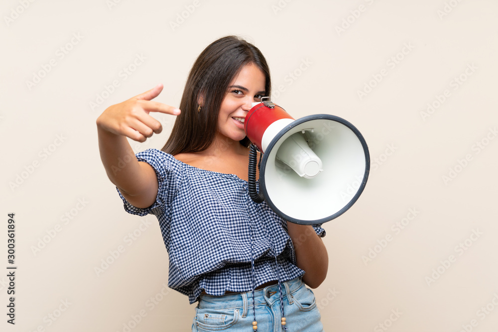 Young girl over isolated background shouting through a megaphone Young girl over isolated background shouting through a megaphone