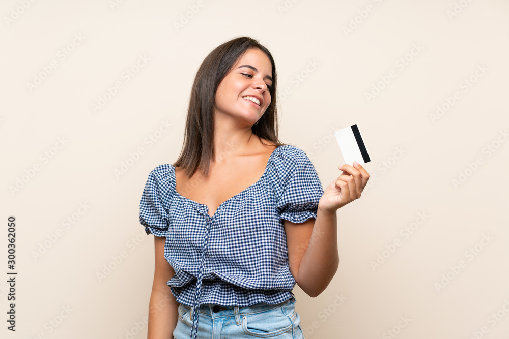 Young girl over isolated background holding a credit card Young girl over isolated background holding a credit card