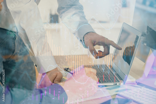 Double exposure of chart with businessman typing on computer in office on background. Concept of hard work.