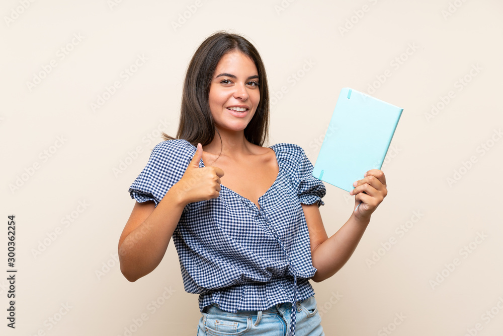 Young girl over isolated background holding and reading a book Young girl over isolated background holding and reading a book