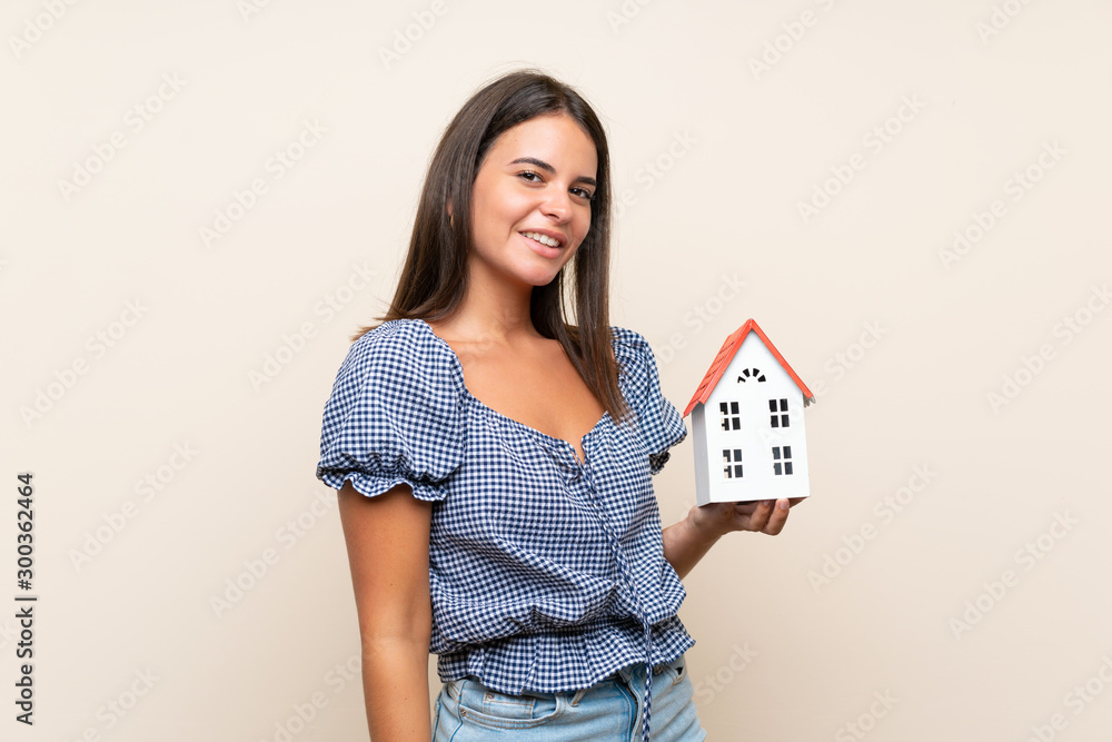 Young girl over isolated background holding a little house Young girl over isolated background holding a little house