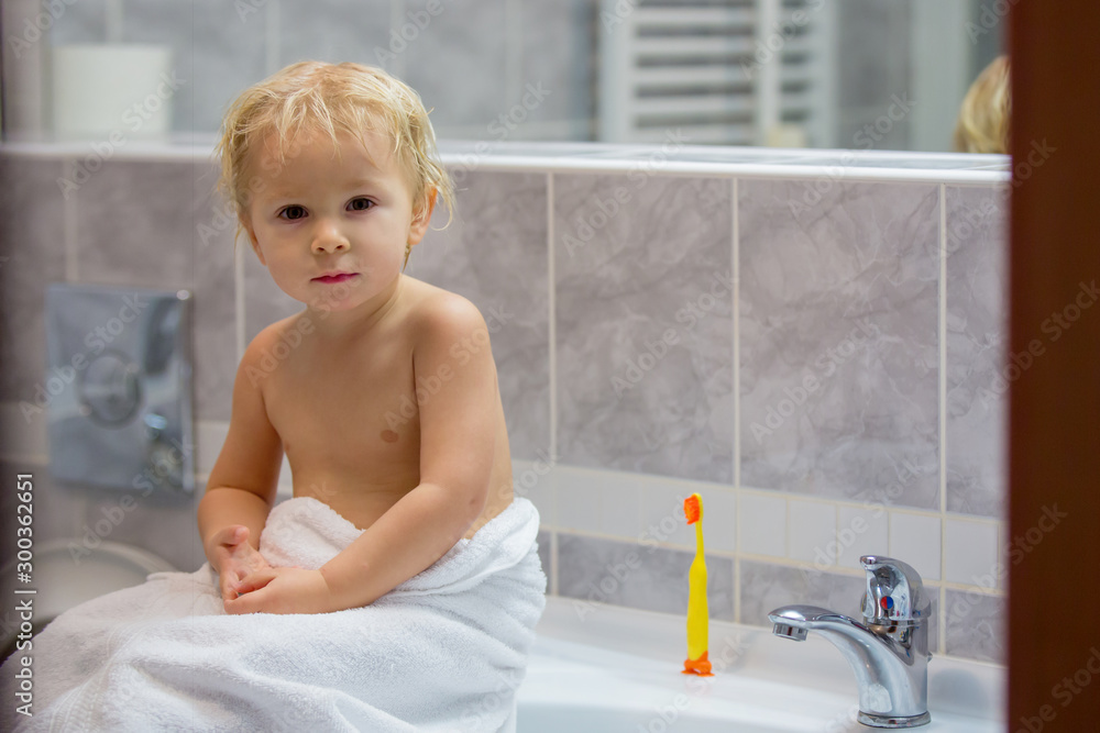Sweet toddler boy, brushing his teeth in bathroom in the evening after bath Sweet toddler boy, brushing his teeth in bathroom in the evening after bath