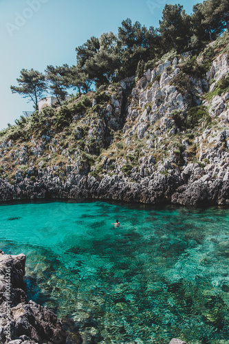 person swimming alone in crystal clear water in Cala Dell'Acquaviva in Puglia, Italy