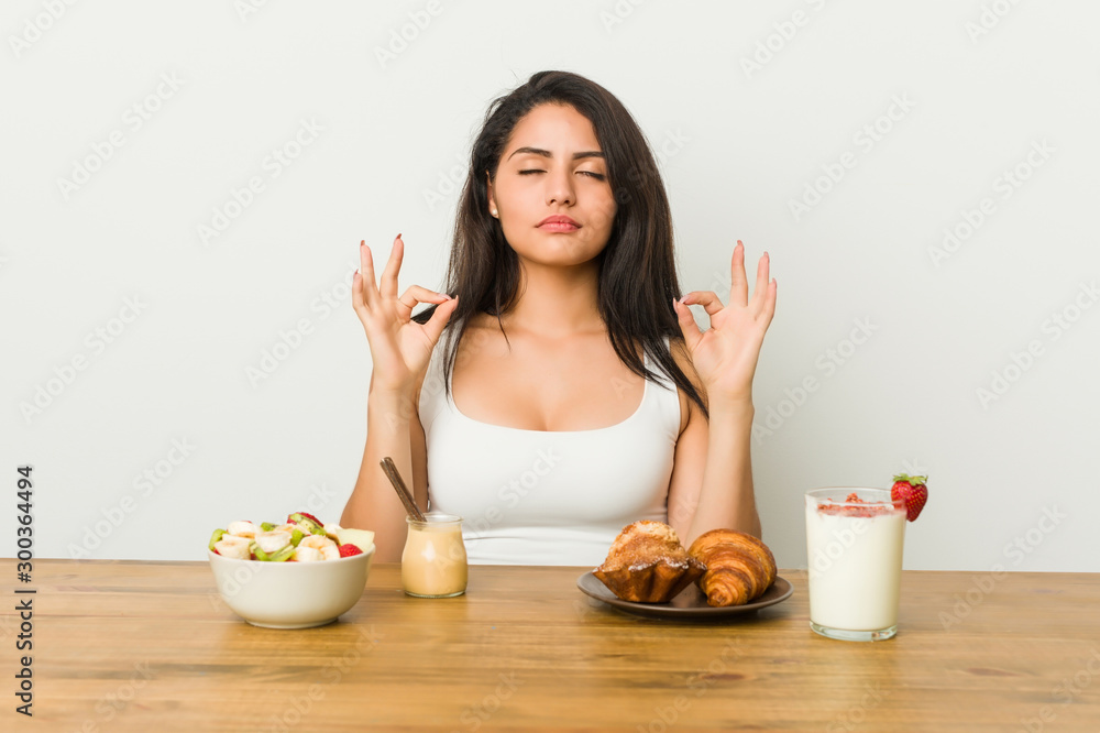 Young curvy woman taking a breakfast relaxes after hard working day, she is performing yoga. Young curvy woman taking a breakfast relaxes after hard working day, she is performing yoga.