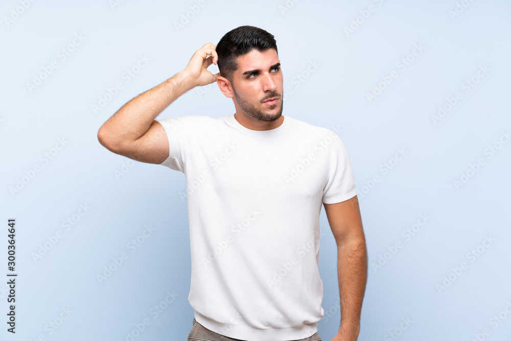 Caucasian handsome man over isolated blue background having doubts while scratching head Caucasian handsome man over isolated blue background having doubts while scratching head