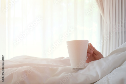 Asia woman holding coffee on white bed, morning concept.