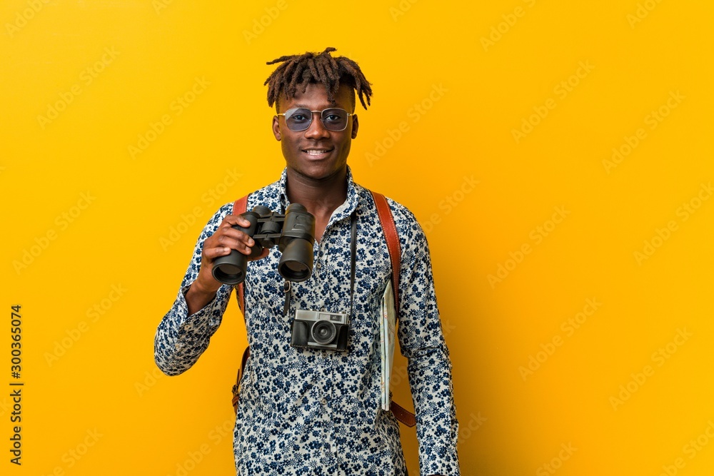 Young african tourist man standing against a yellow background holding a binoculars Young african tourist man standing against a yellow background holding a binoculars
