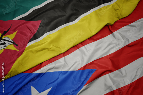 waving colorful flag of puerto rico and national flag of mozambique.