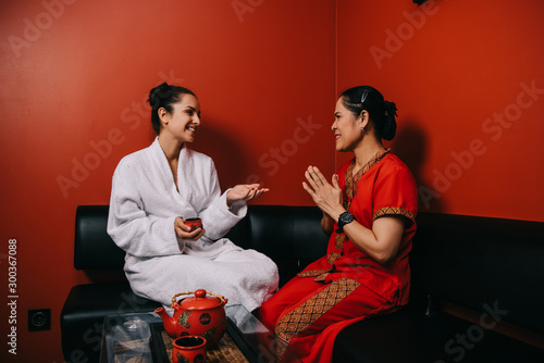 attractive woman in bathrobe and asian masseur talking in spa