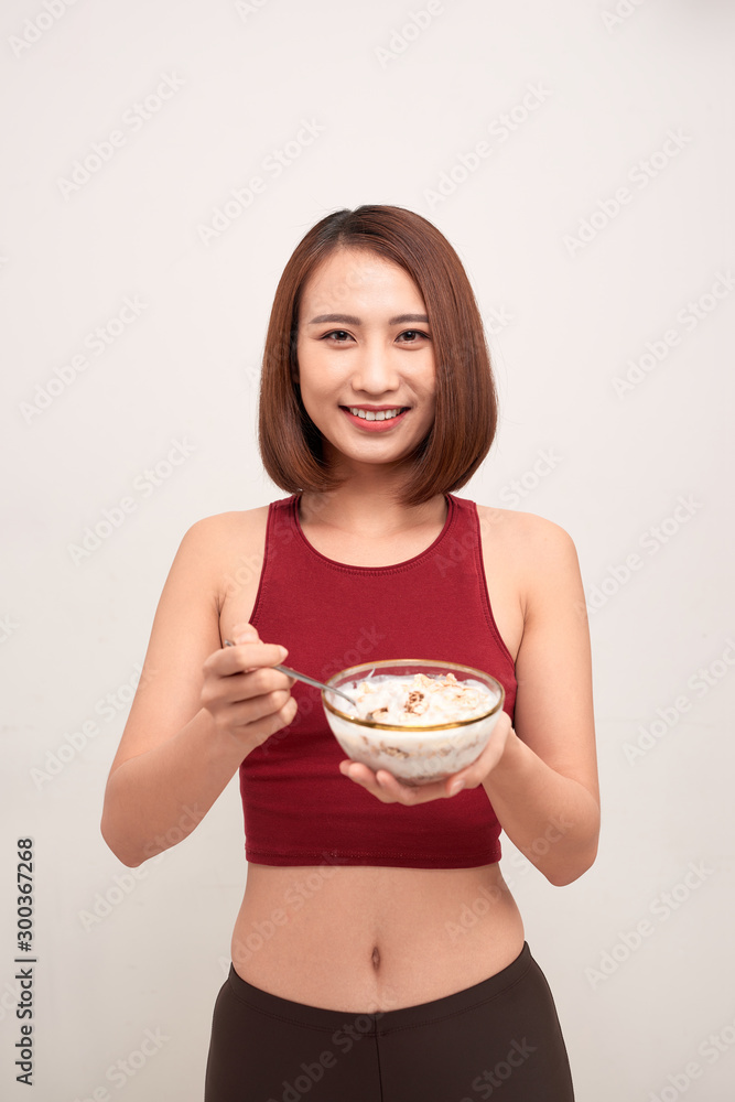 Young woman is resting and eating a healthy oatmeal after a workout. Young woman is resting and eating a healthy oatmeal after a workout.