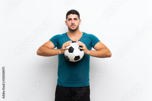 Handsome young football player man over isolated white wall © luismolinero