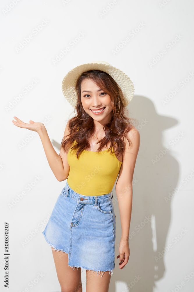 Young Asian woman wearing round hat with expression of surprise isolated on white background. Young Asian woman wearing round hat with expression of surprise isolated on white background.