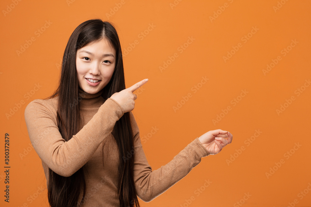 Young pretty chinese woman excited pointing with forefingers away. Young pretty chinese woman excited pointing with forefingers away.