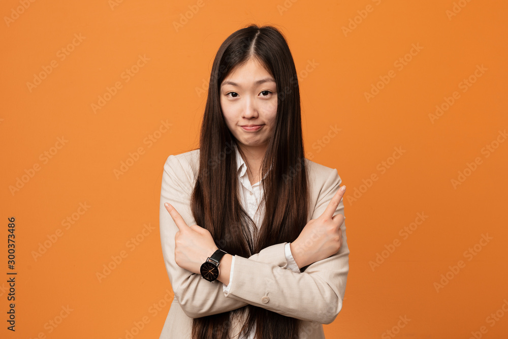 Young business chinese woman points sideways, is trying to choose between two options. Young business chinese woman points sideways, is trying to choose between two options.