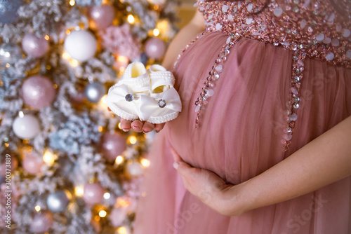 Pregnancy. Pregnant belly with hemp on the background of Christmas decorations.