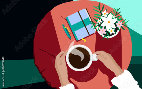 Human hands with cup of hot coffee and flowers at the table.