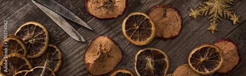 top view of dried citrus and apple slices near snowflake, rope and scissors on wooden surface, panoramic shot